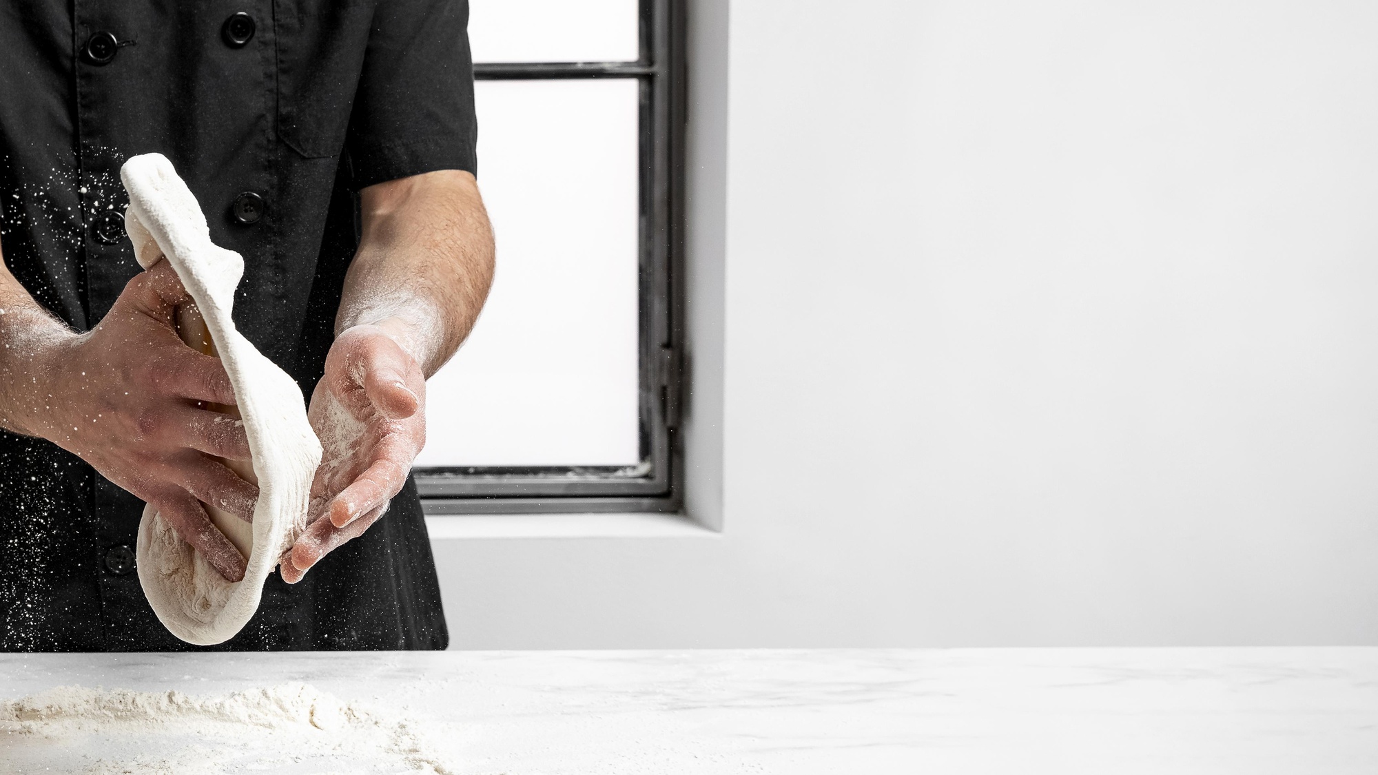 Chef al lavoro in cucina moderna, close-up di mani che preparano impasto